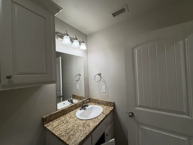 a bathroom with a granite countertop sink and a mirror