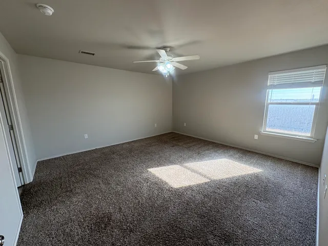 an empty room with a fan & a window