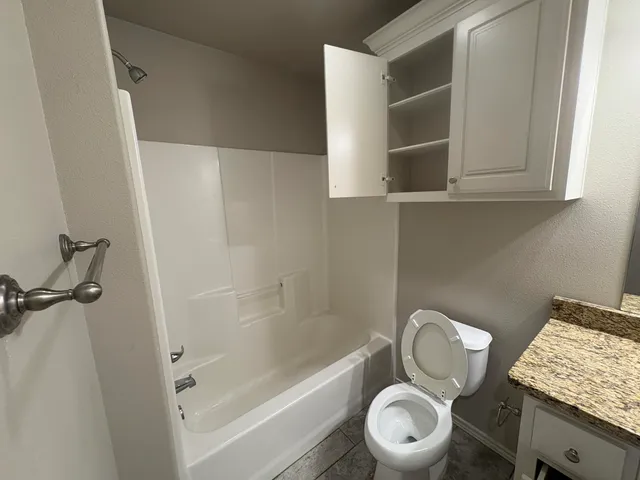 a bathroom with a granite countertop sink mirror vanity and toilet