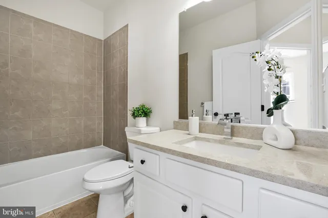 a bathroom with a granite countertop bathtub sink vanity mirror and toilet