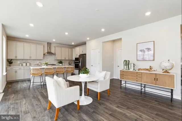 a living room with stainless steel appliances kitchen island granite countertop a sink and dishwasher with wooden floor