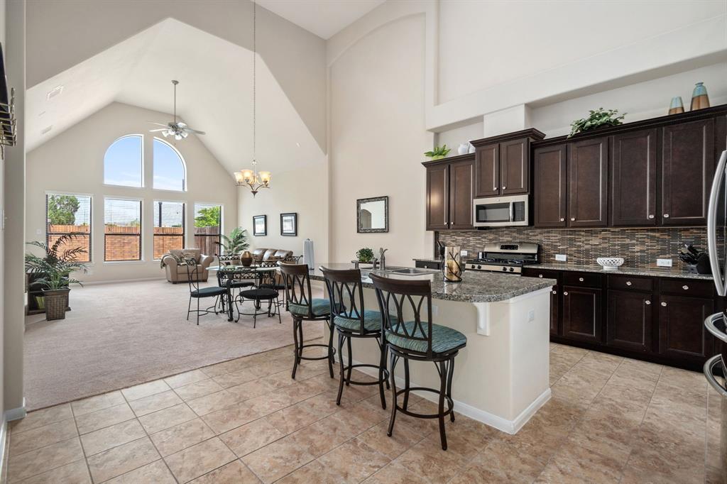 a open kitchen with granite countertop a stove a sink a dining table and chairs