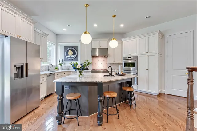 a kitchen with stainless steel appliances a dining table chairs refrigerator and microwave