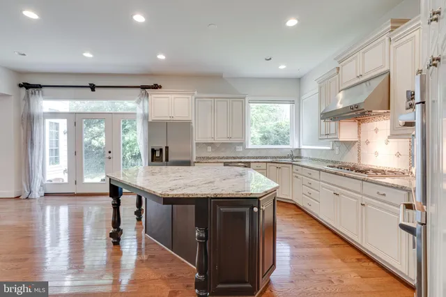 a kitchen with granite countertop center island wooden floor and stainless steel appliances
