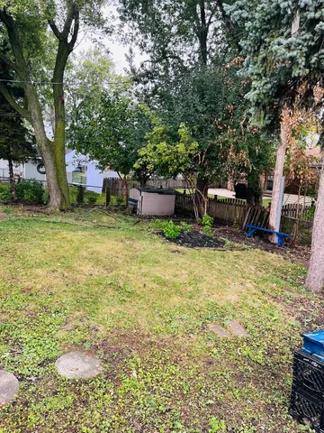 a view of a backyard with table and chairs and a barbeque with potted plants and large trees