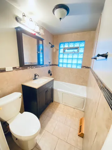 a bathroom with a sink vanity mirror bathtub and toilet