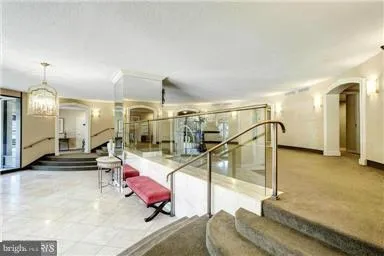 a room with lots of white furniture and a chandelier