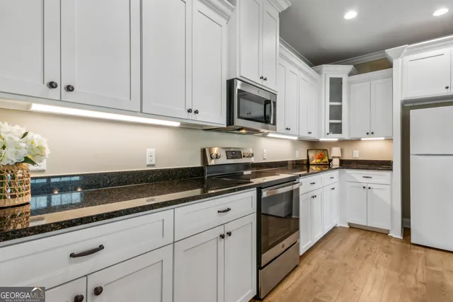 a kitchen with granite countertop white cabinets stainless steel appliances and sink