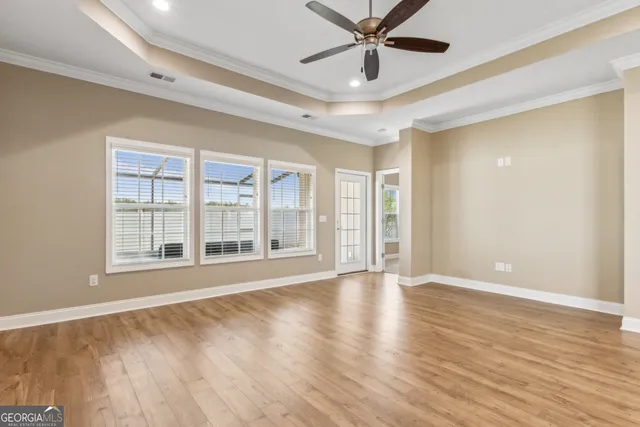 a view of an empty room with a window and wooden floor