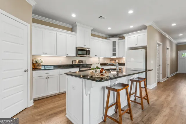 a kitchen with stainless steel appliances granite countertop a stove top oven a refrigerator a sink and a dining table with wooden floor