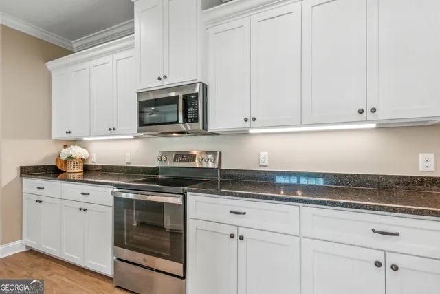 a kitchen with granite countertop white cabinets and a stove top oven