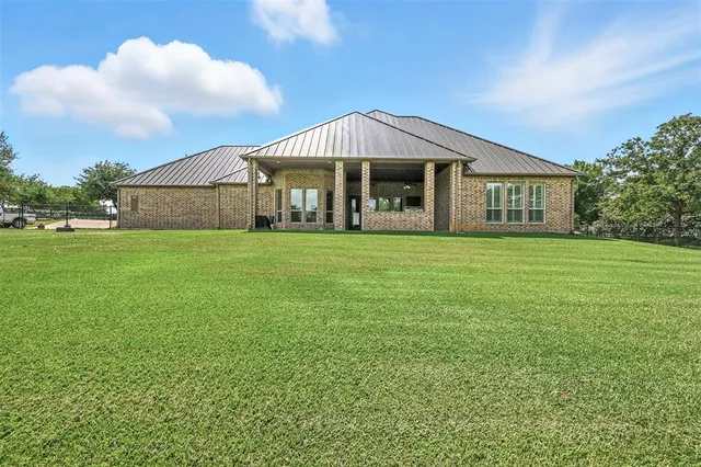 a view of a house with a big yard plants and large trees