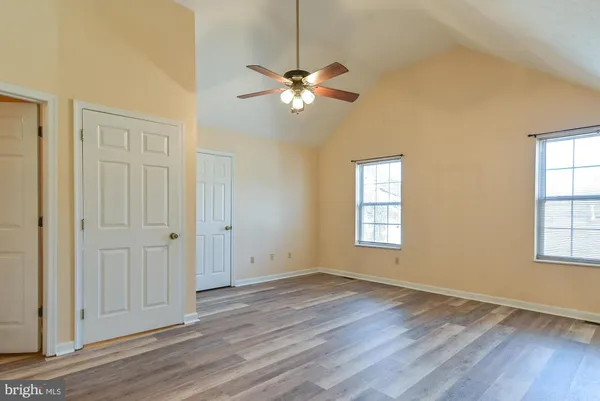 a view of empty room with wooden floor and fan