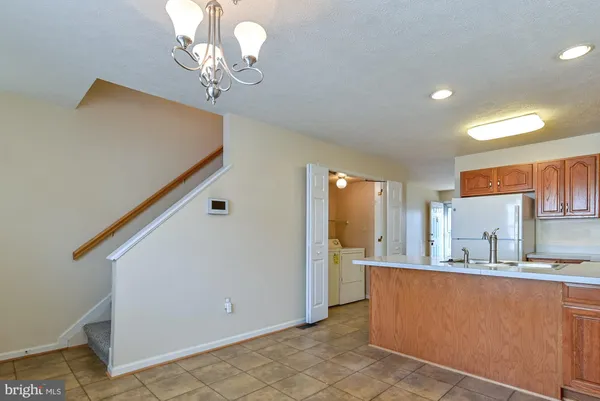 a kitchen with stainless steel appliances kitchen island granite countertop a refrigerator a sink dishwasher a stove and a dining table with wooden floor