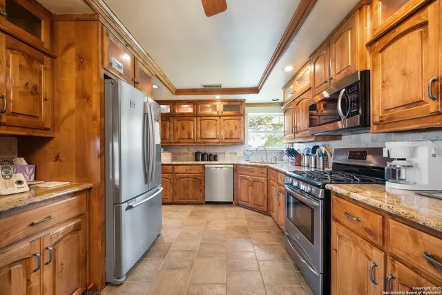 a kitchen with stainless steel appliances granite countertop a refrigerator a stove and a sink