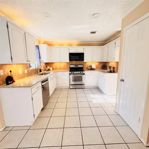 a kitchen with a sink a stove top oven and cabinets