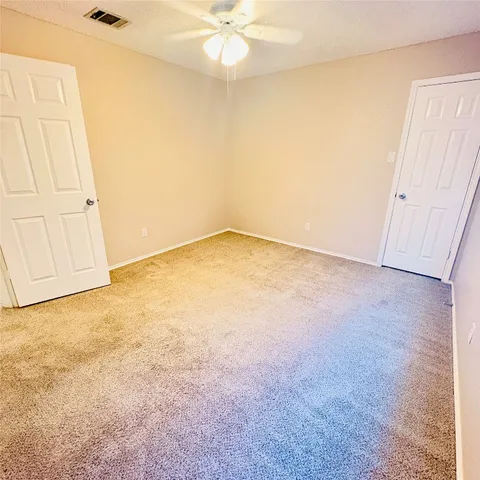 an empty room with a ceiling fan and carpet