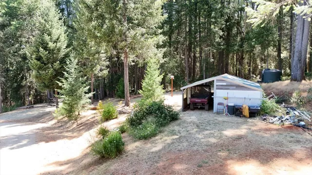a view of a house with a yard and large trees