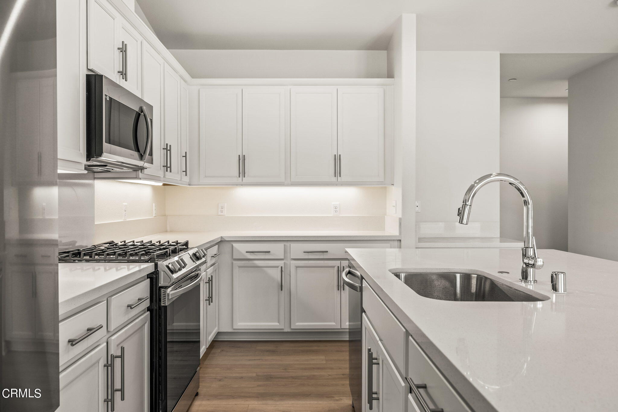 311 North F Street, Unit 202 Oxnard, CA 93030 - Photo 11 of 32 a kitchen with white cabinets stainless steel appliances and sink
