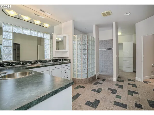 a bathroom with a granite countertop sink a mirror and a shower