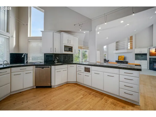 a kitchen with stainless steel appliances granite countertop a stove a sink and white cabinets
