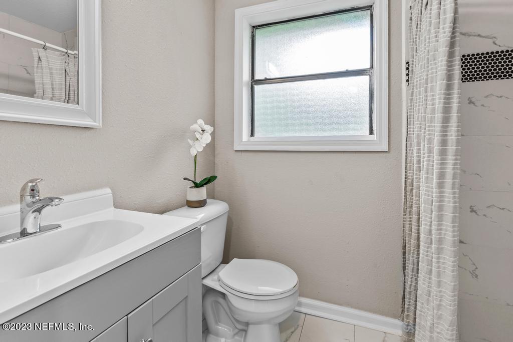 2142 Benedict Road Jacksonville, FL 32209 - Photo 20 of 34 a bathroom with a toilet a sink a window and mirror