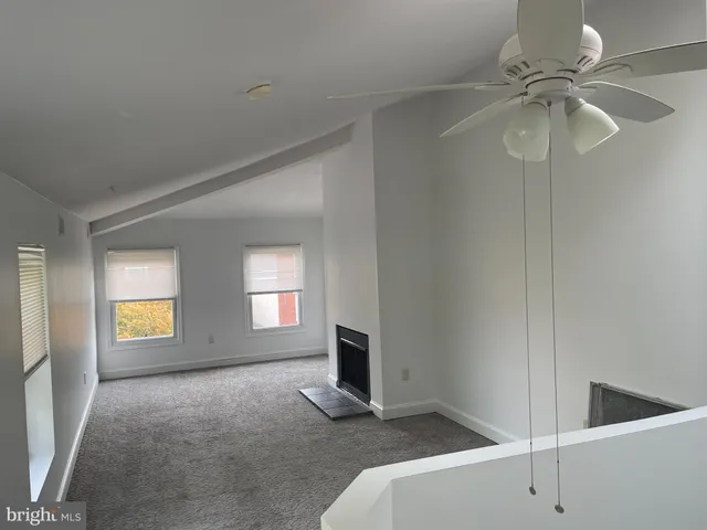 a view of an empty room with window and chandelier fan