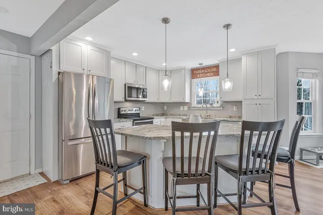 a kitchen with stainless steel appliances granite countertop a dining table chairs refrigerator and sink