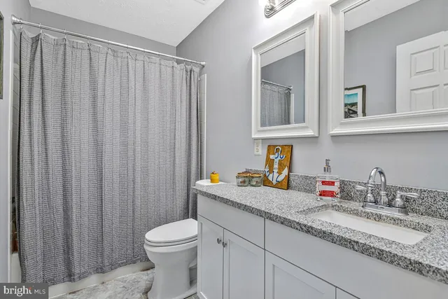 a bathroom with a granite countertop sink toilet and mirror