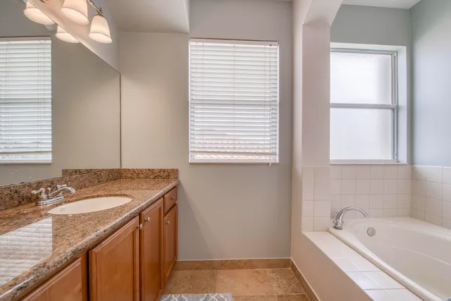 a bathroom with a granite countertop sink and a bathtub