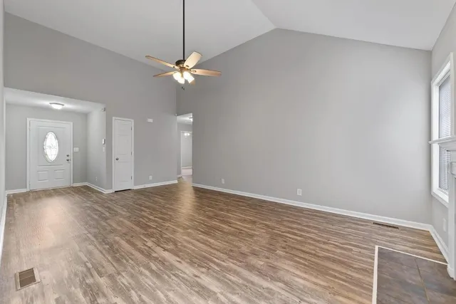 a view of an empty room with window and wooden floor