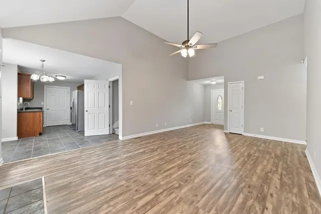 a view of an empty room with wooden floor and a ceiling fan