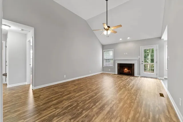 a view of an empty room with wooden floor fireplace and a window