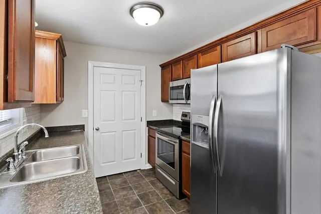 a kitchen with stainless steel appliances granite countertop a refrigerator a sink and white cabinets
