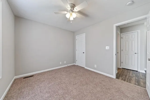 an empty room with closet and a chandelier fan