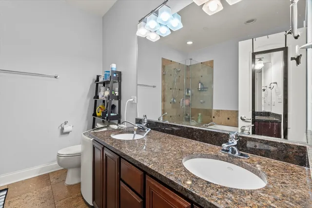 a bathroom with a granite countertop double vanity sink toilet and a mirror