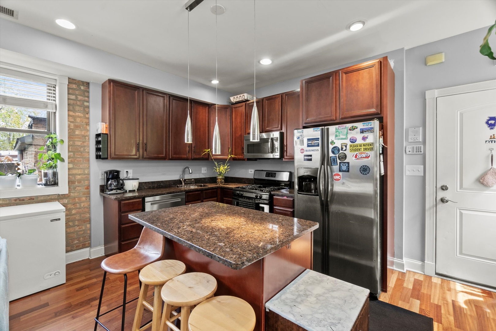 6414 North Hoyne Avenue, Unit 3W Chicago, IL 60645 - Photo 3 of 16 a kitchen with stainless steel appliances granite countertop a refrigerator a stove a sink a dining table and chairs with wooden floor