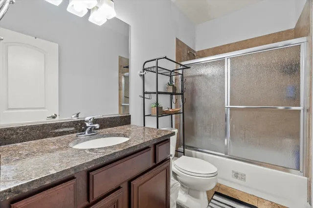 a bathroom with a granite countertop sink toilet mirror and shower