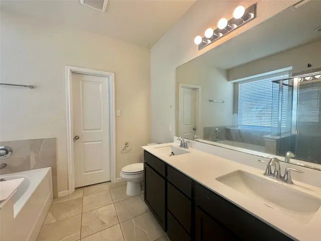 a bathroom with a double vanity sink a large mirror and a bathtub