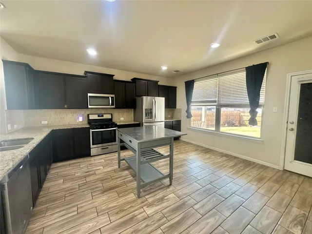a kitchen with stainless steel appliances wooden floor and large window