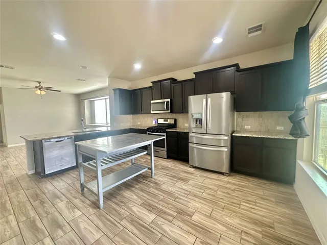 a kitchen with granite countertop a refrigerator and a stove top oven