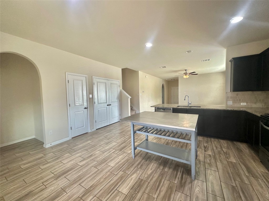 8164 Daisy Cutter Crossing Georgetown, TX 78626 - Photo 4 of 19 a view of an empty room and kitchen with wooden floor and furniture