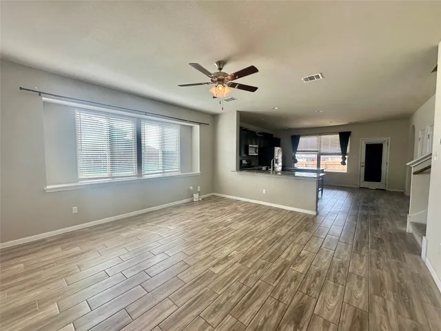 a view of an empty room with window and wooden floor
