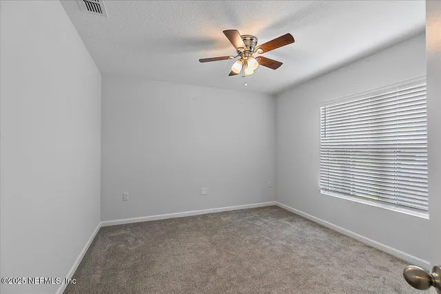 an empty room with windows and fan