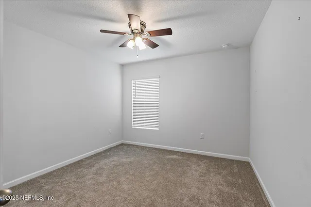 an empty room with a window and a fan