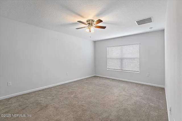 an empty room with windows and fan