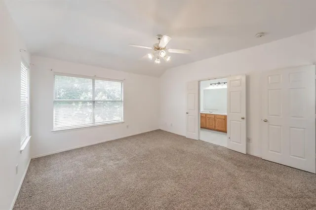 an empty room with windows and ceiling fan