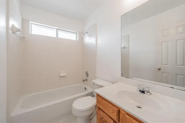 a bathroom with a bathtub shower sink vanity mirror and toilet