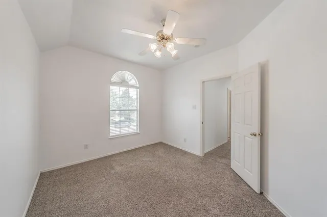 an empty room with a chandelier fan and windows