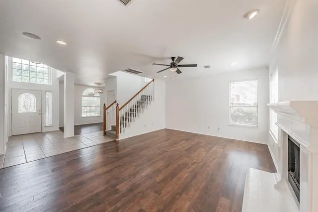 a view of an empty room with wooden floor and a fireplace